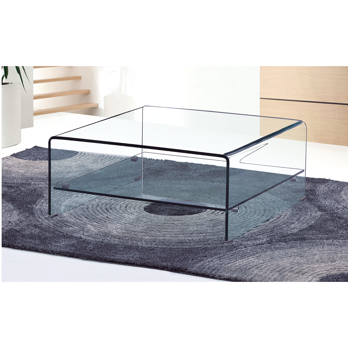 Clear glass coffee table on a grey textured rug with a white wall background