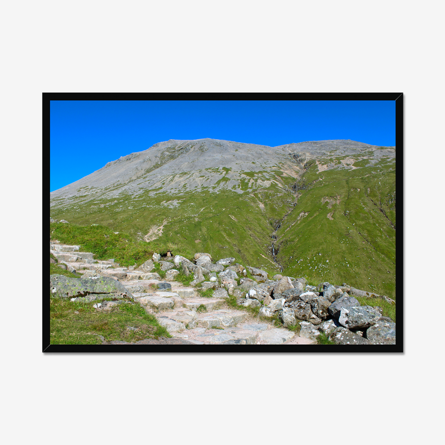 Framed photograph of a mountain landscape with a clear blue sky.