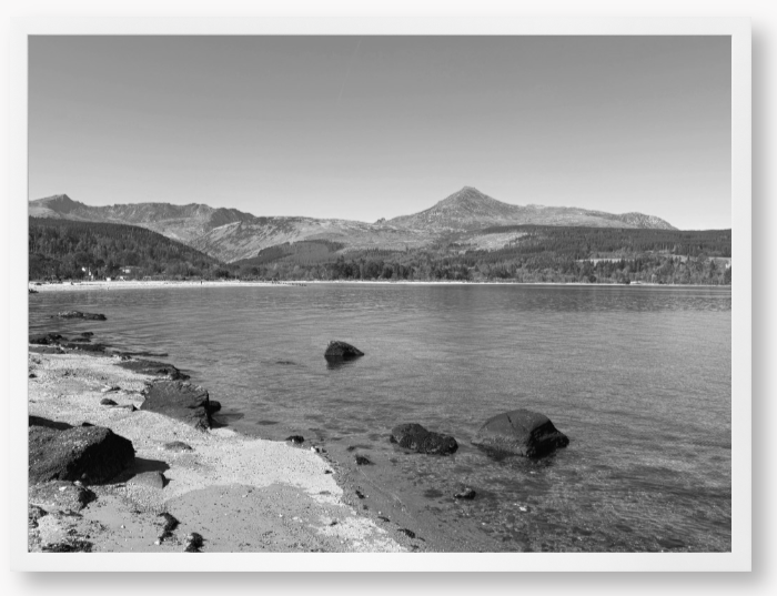 A black and white framed photo of Brodick Bay on the Isle of Arran, showing the beach and mountains in the background with a clear sky.