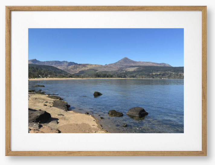 A framed photo of Brodick Bay on the Isle of Arran, showing the beach and mountains in the background with a clear blue sky.
