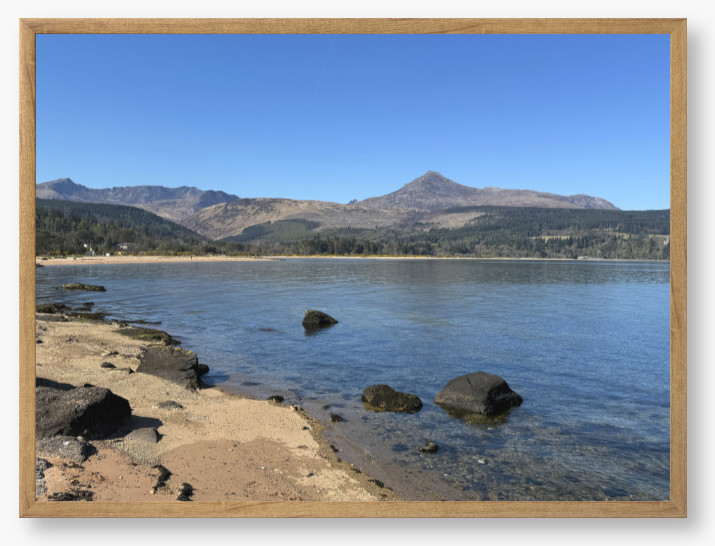 A framed photo of Brodick Bay on the Isle of Arran, showing the beach and mountains in the background with a clear blue sky.