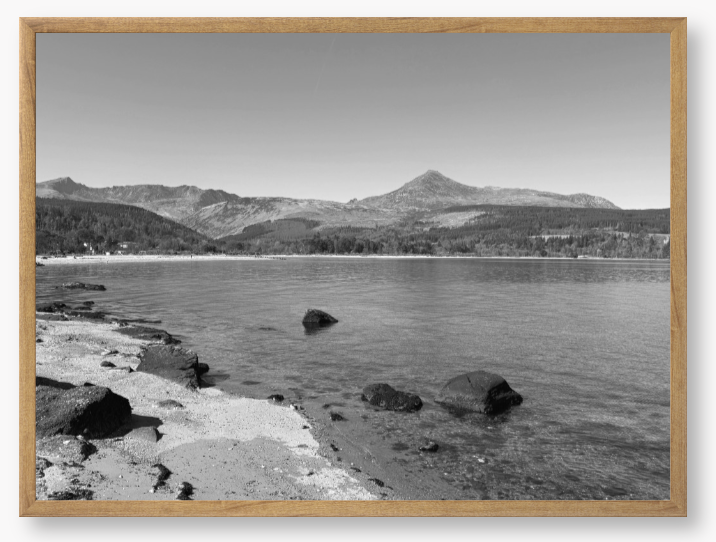 A black and white framed photo of Brodick Bay on the Isle of Arran, showing the beach and mountains in the background with a clear sky.