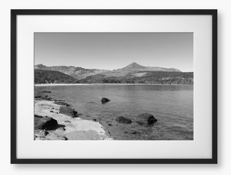 A black and white framed photo of Brodick Bay on the Isle of Arran, showing the beach and mountains in the background with a clear sky.