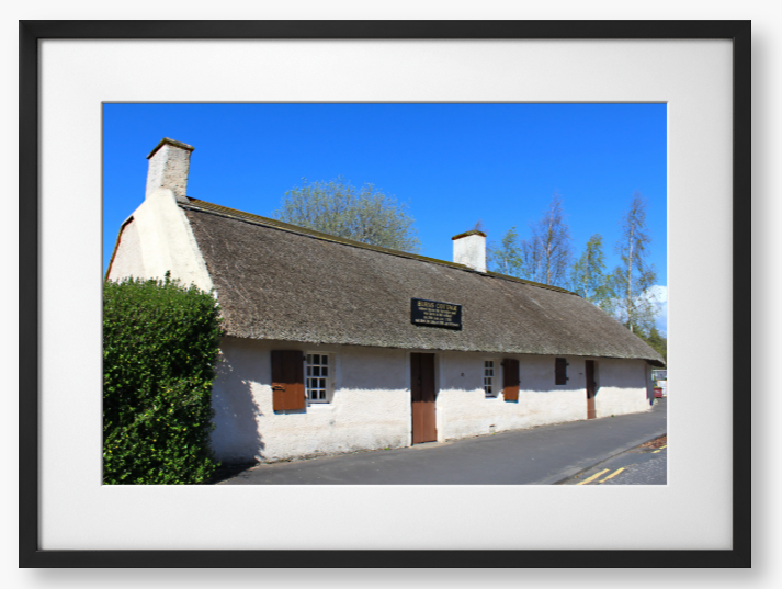 Framed Photo Of A Traditional thatched cottage with a blue sky and trees in the background