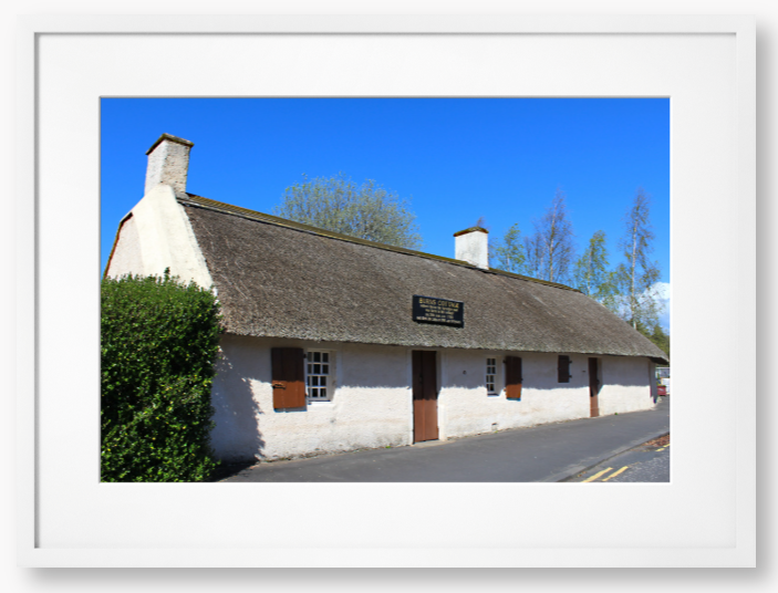 Framed Photo Of A Traditional thatched cottage with a blue sky and trees in the background