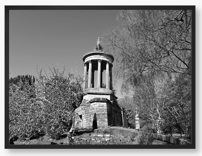 Black and White Framed Photo Of A Stone monument in a park with trees