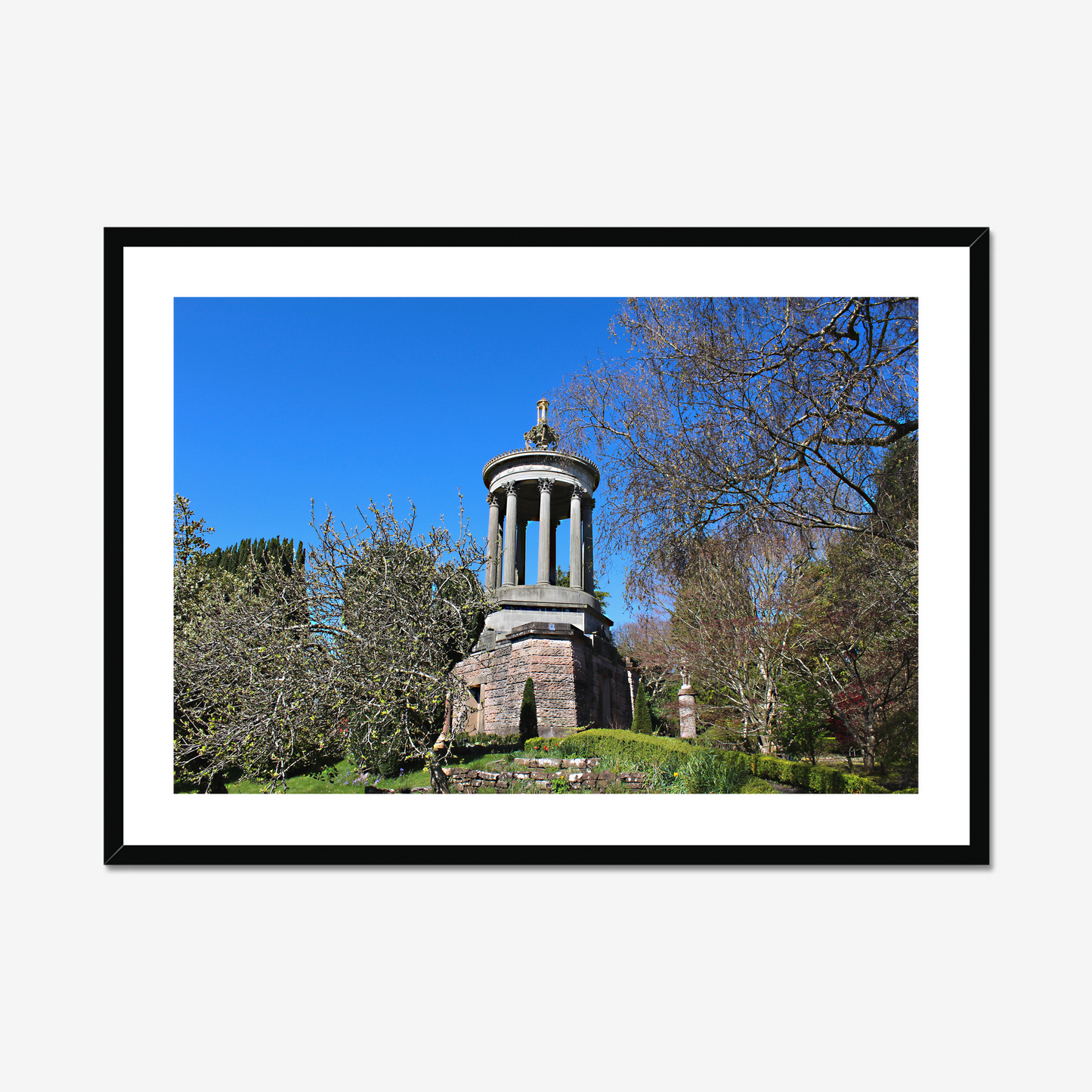 Stone monument in a park with trees and blue sky