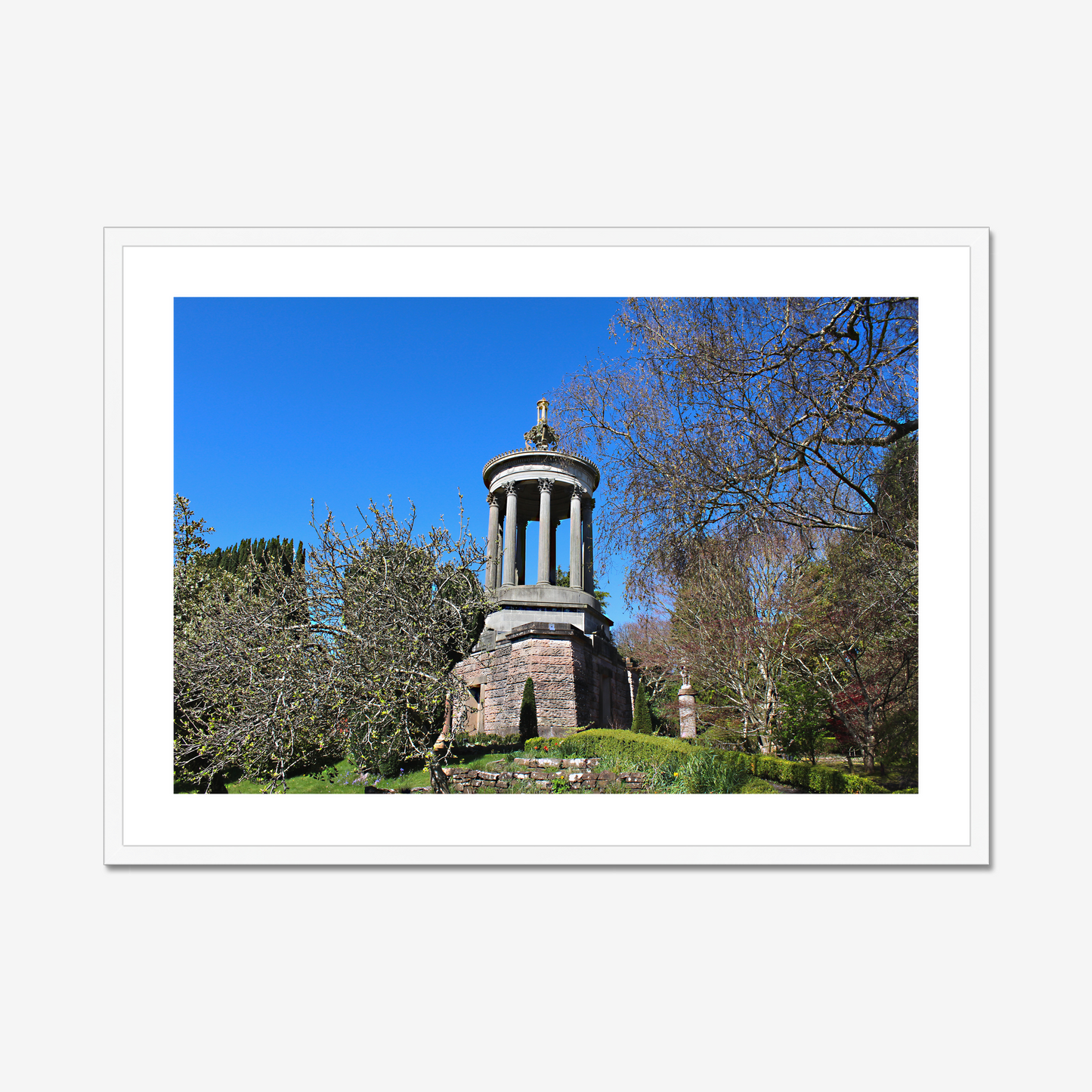 Stone monument in a park with trees and blue sky