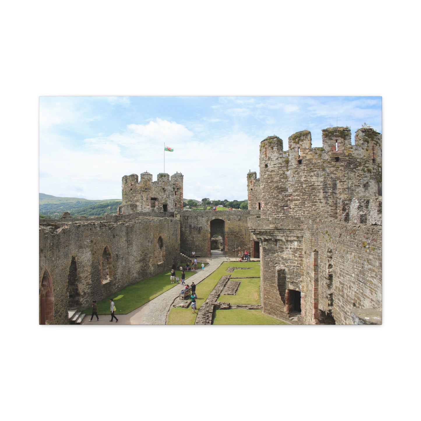Medieval castle with tourists walking around, under a blue sky.