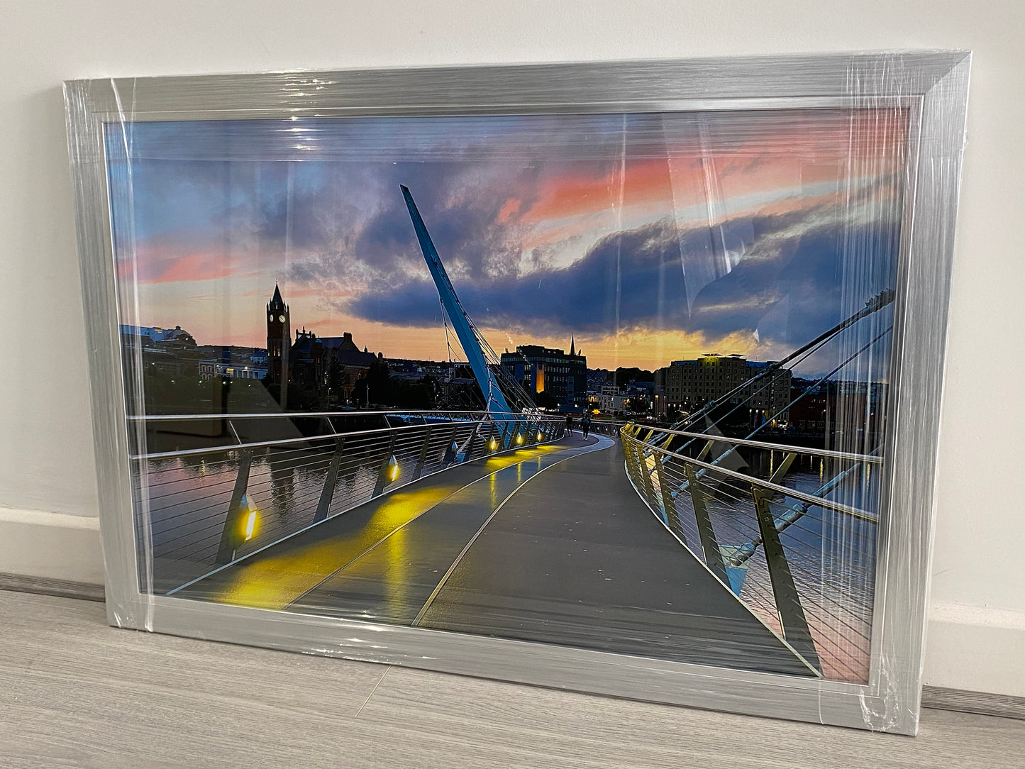 Framed photograph of a bridge with a cityscape at sunset.
