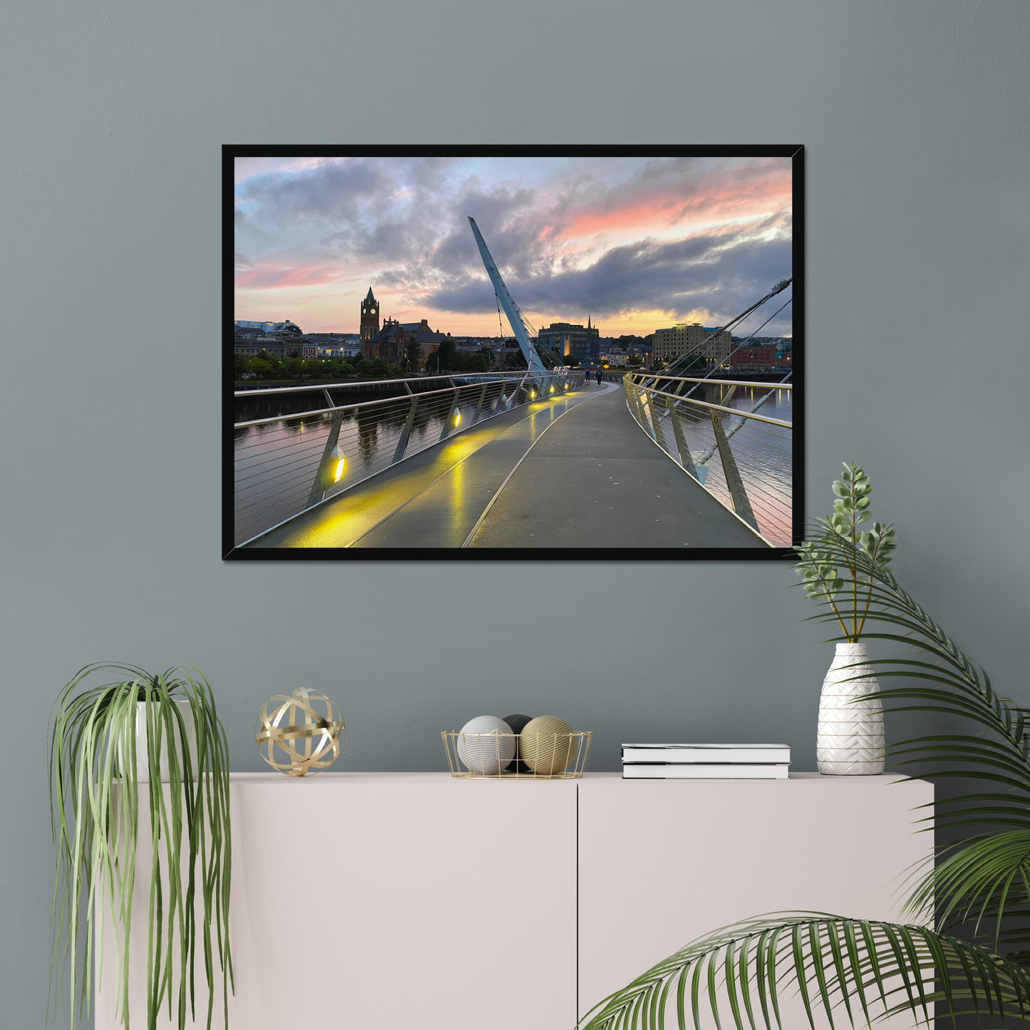 Framed artwork of a cityscape with a bridge on a gray wall above a white console table.