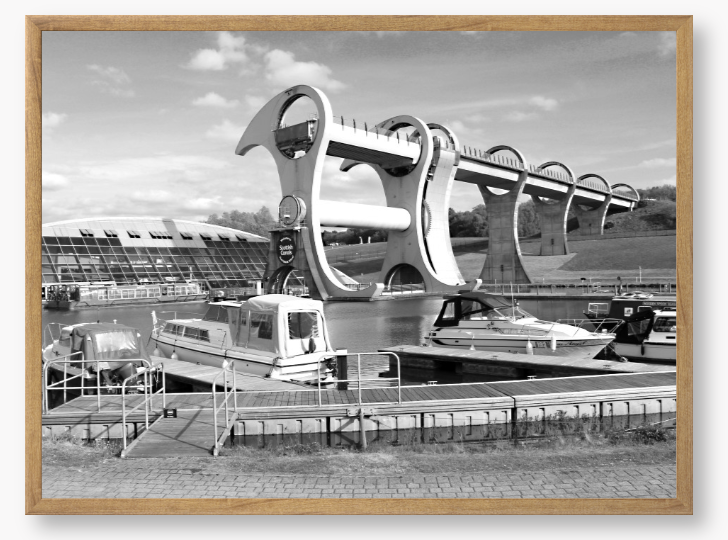 Black and White framed photo of the Falkirk Wheel boat lift with boats docked at a marina under a clear sky.