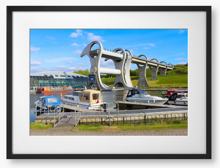 A framed photo of the Falkirk Wheel boat lift with boats docked at a marina under a blue sky.