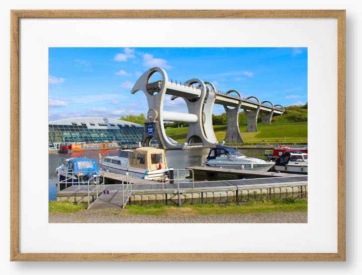 A framed photo of the Falkirk Wheel boat lift with boats docked at a marina under a blue sky.