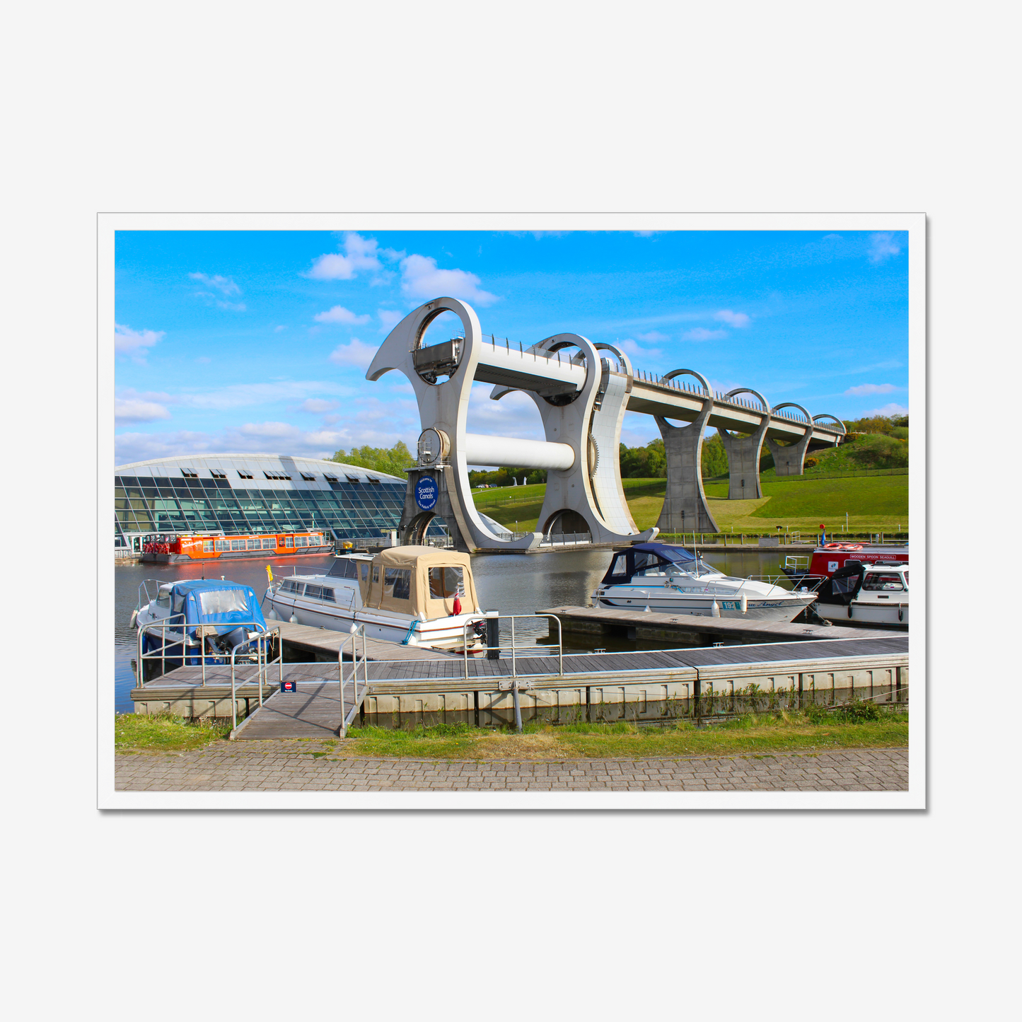 Falkirk Wheel boat lift with boats docked at a pier on a clear day.