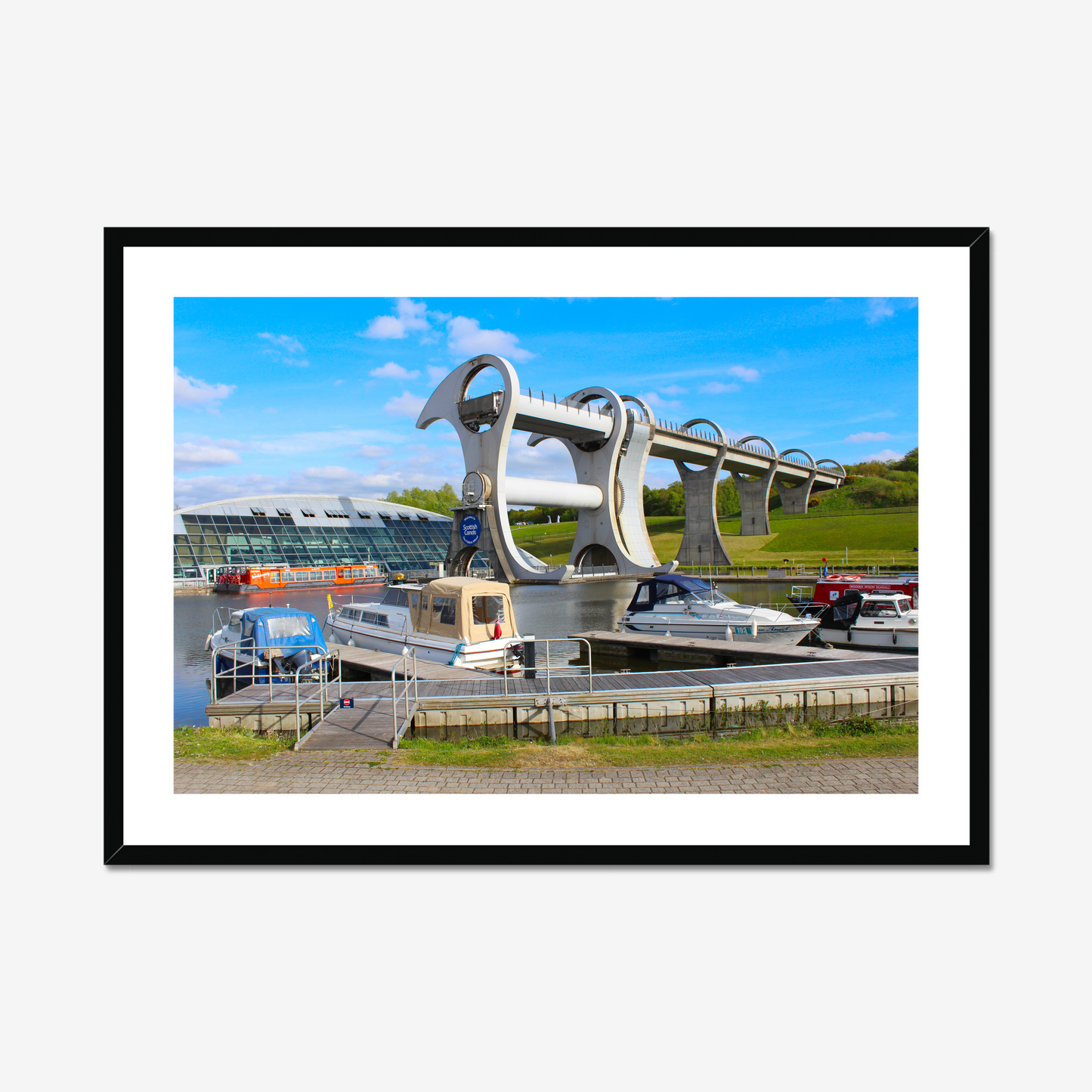 Falkirk Wheel boat lift with boats docked at a pier on a clear day.