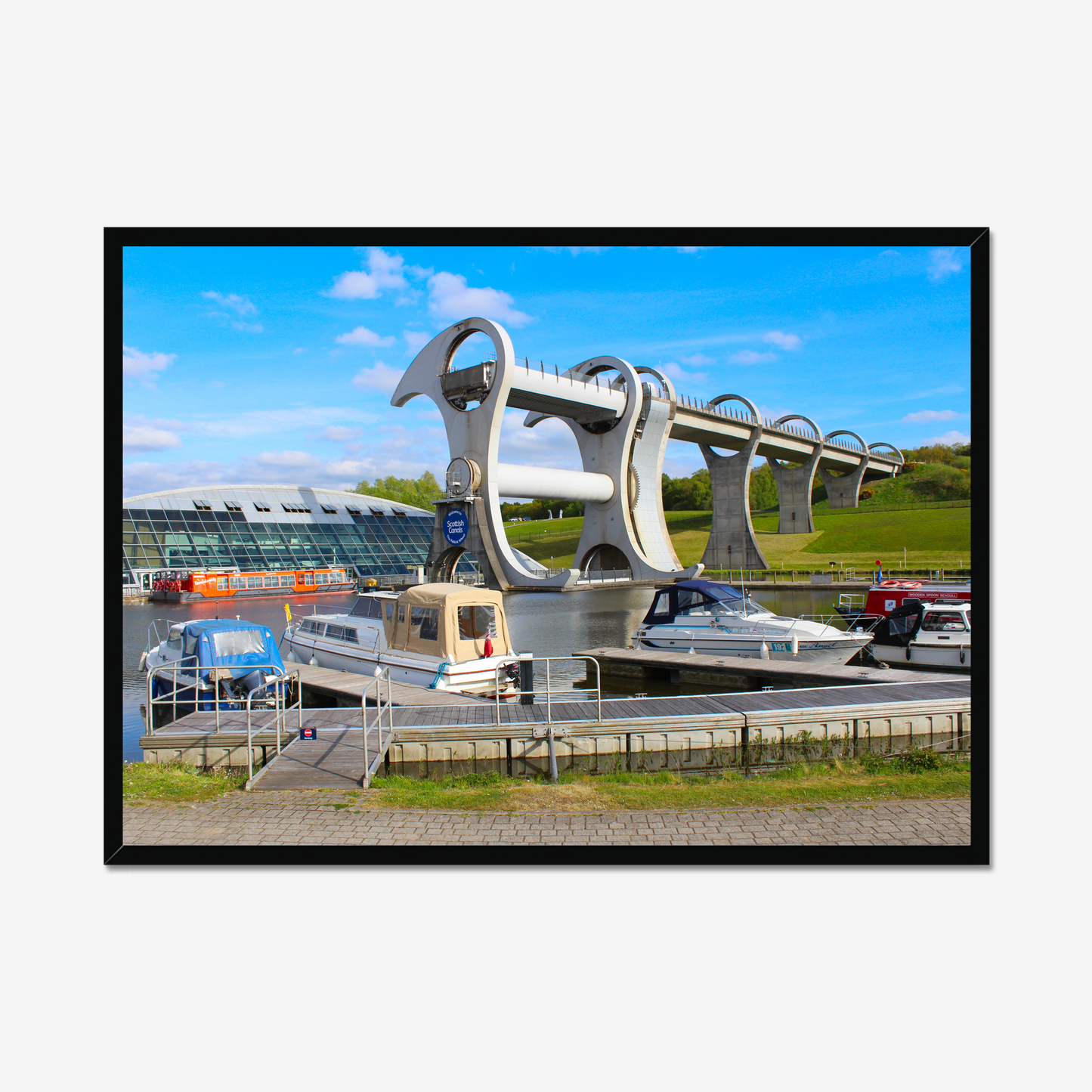 Falkirk Wheel boat lift with boats docked at a pier on a clear day.