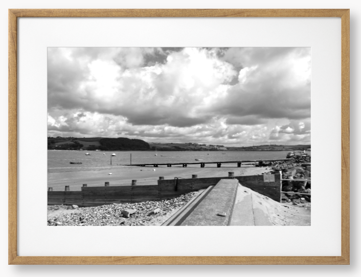 Black and White Framed Photo of a Beach scene with a large body of water, sky with clouds, and distant hills.