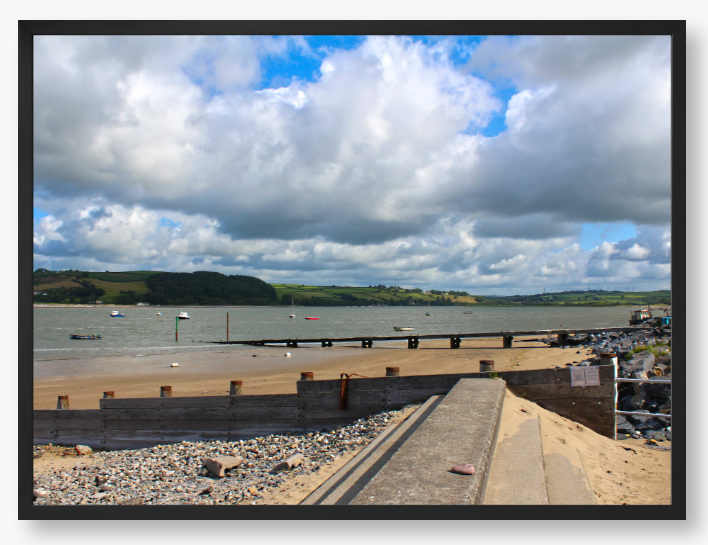 Framed Photo of a Beach scene with a large body of water, sky with clouds, and distant hills.