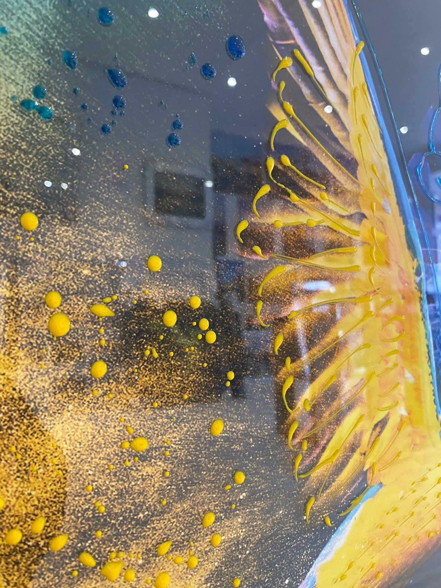 Close-up of a yellow parrot with water droplets on a reflective surface.