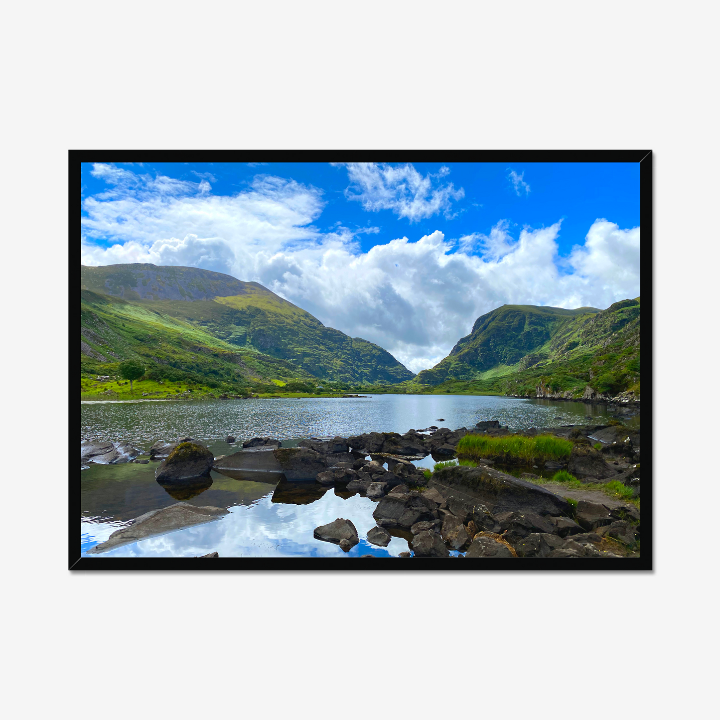 Framed photograph of a lake with mountains in the background and a blue cloudy sky.