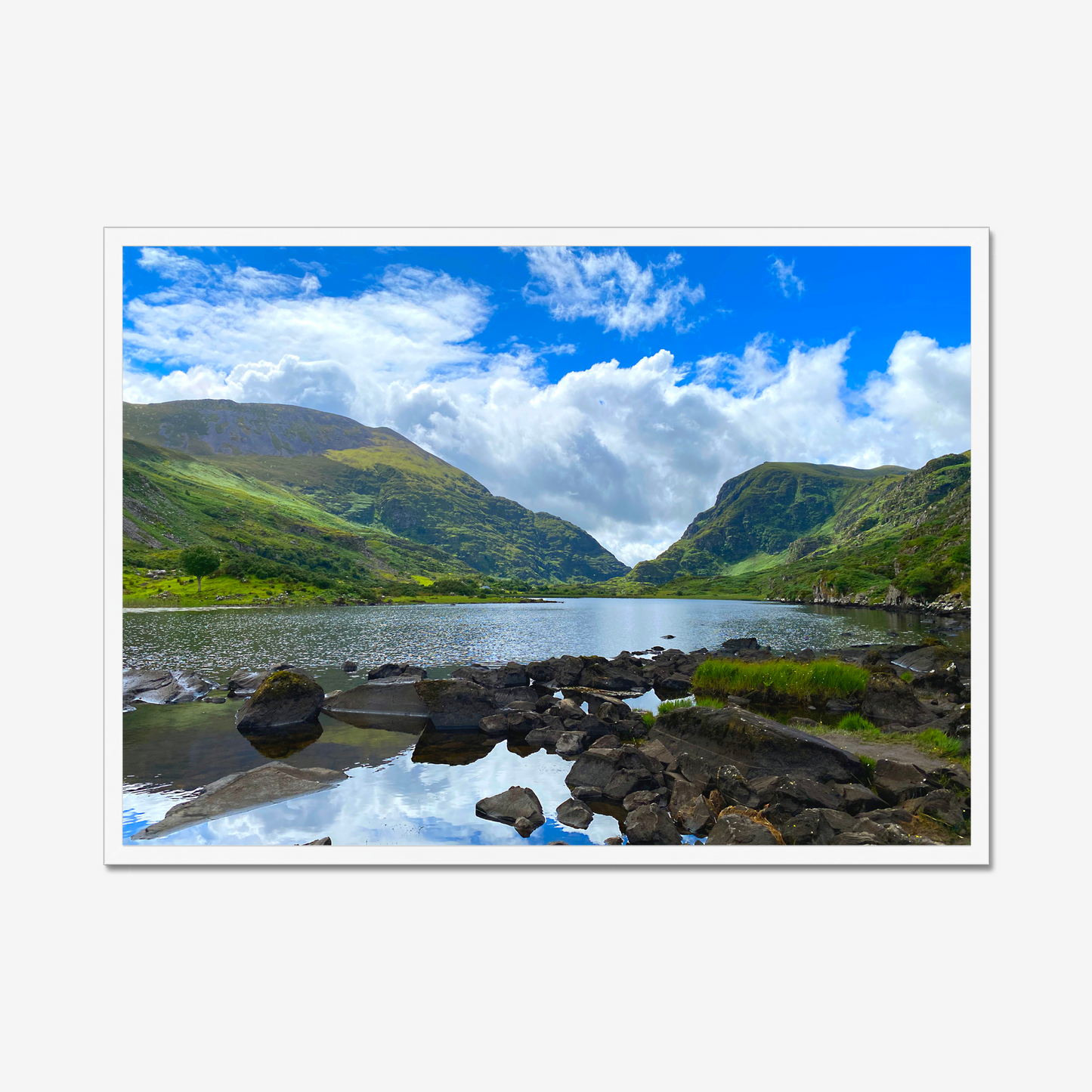 Framed photograph of a lake with mountains in the background and a blue cloudy sky.