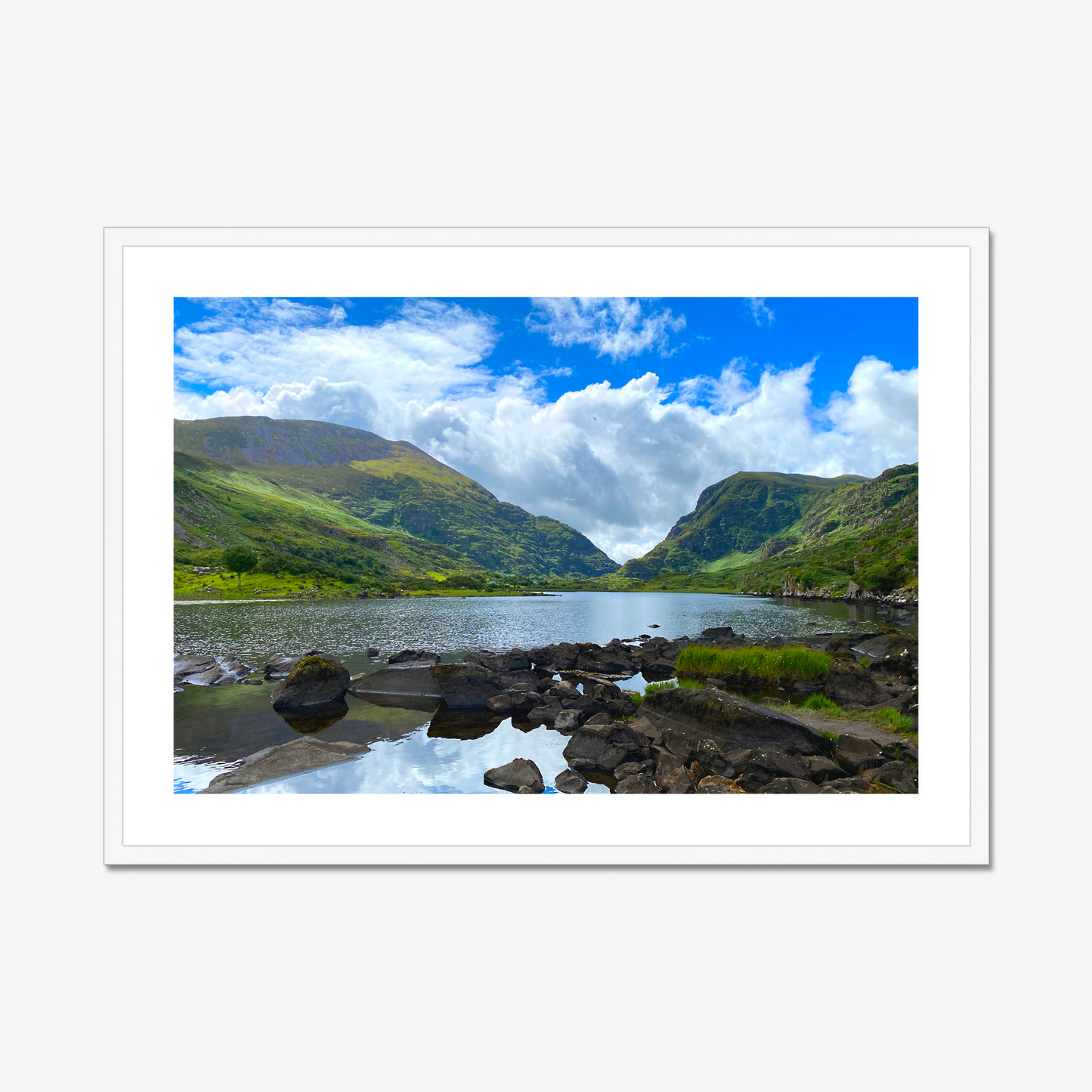 Framed photograph of a lake with mountains in the background and a blue cloudy sky.