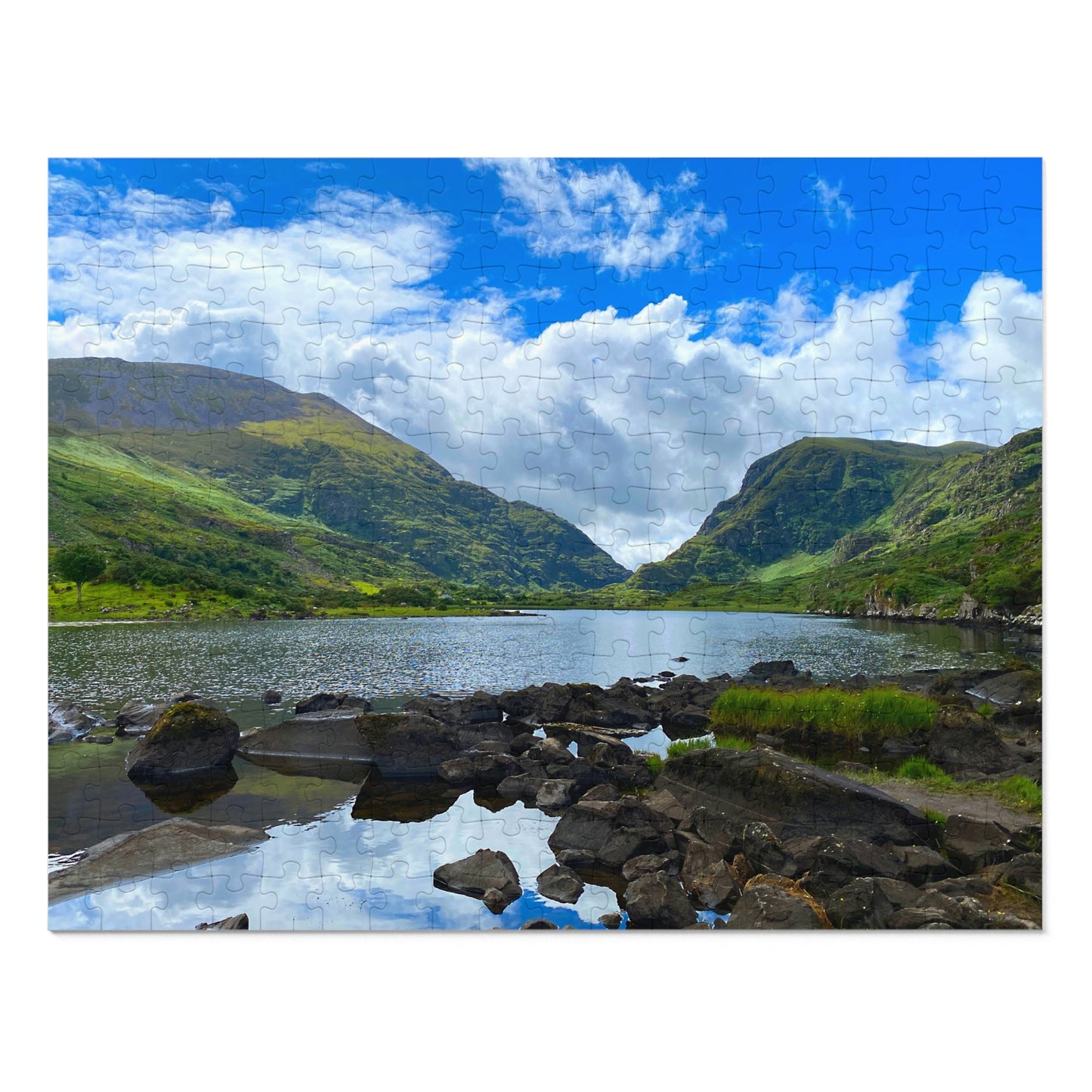 Scenic landscape with a lake and mountains under a blue sky with clouds.