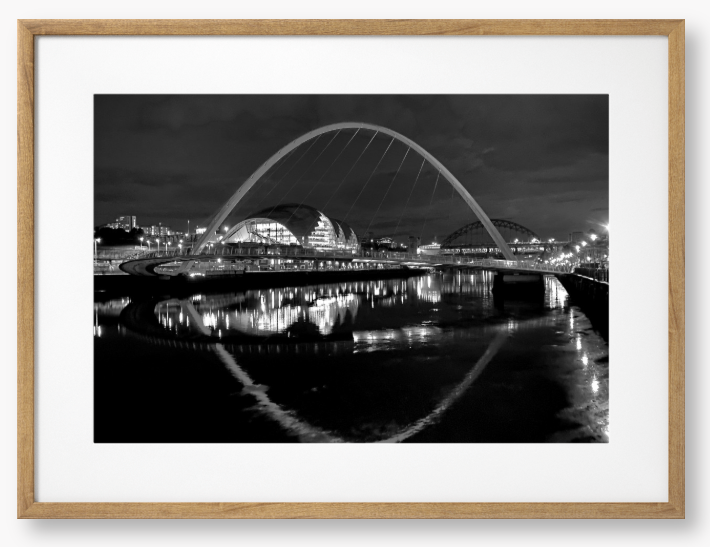 Black and white photograph of a modern bridge over a river at night.