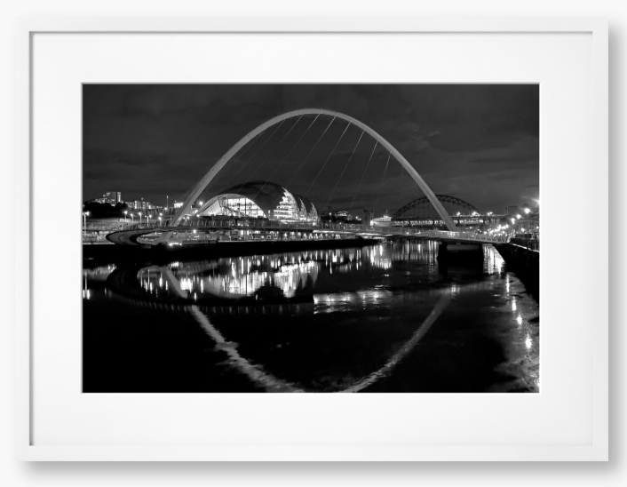Black and white photograph of a modern bridge over a river at night.