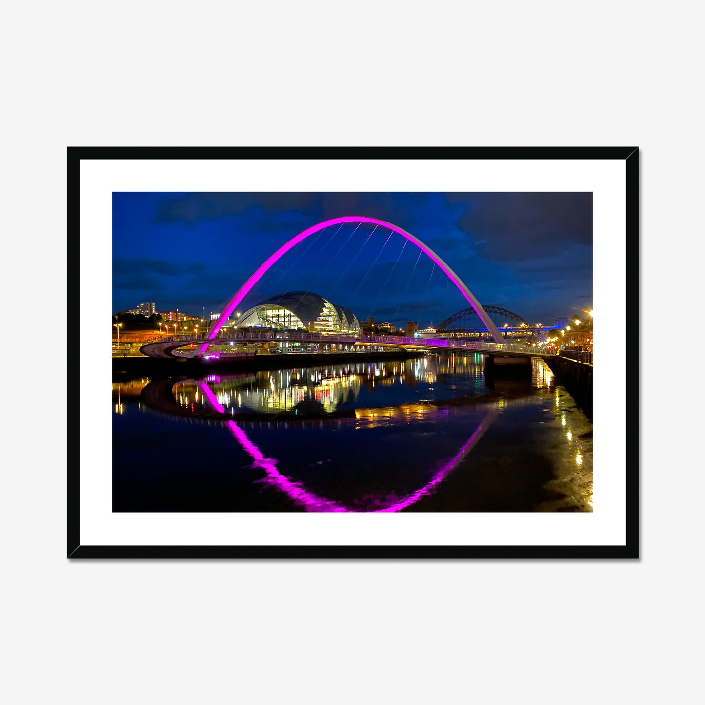 Framed photograph of a colourful arch bridge at night with a reflective water surface.