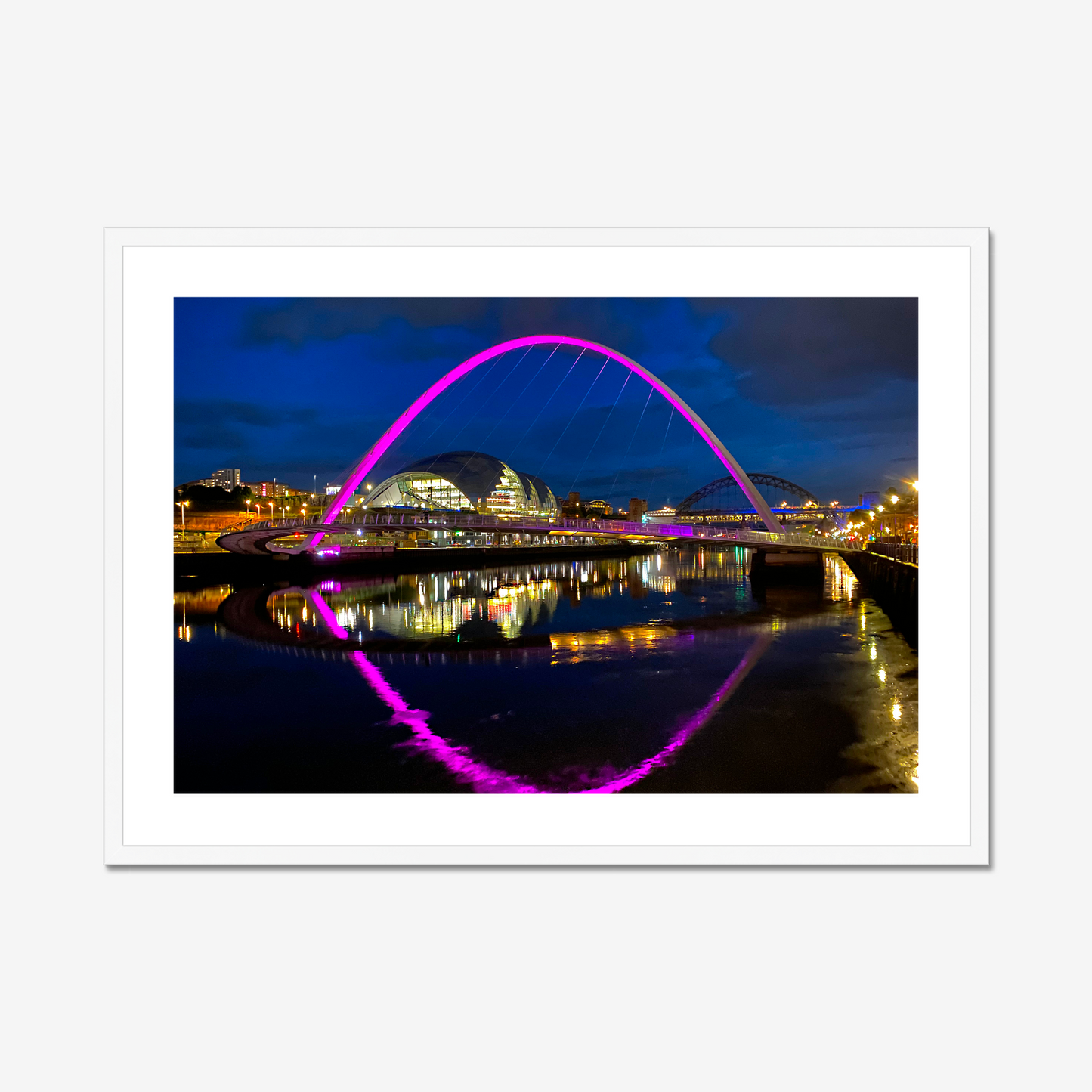 Framed photograph of a colourful arch bridge at night with a reflective water surface.