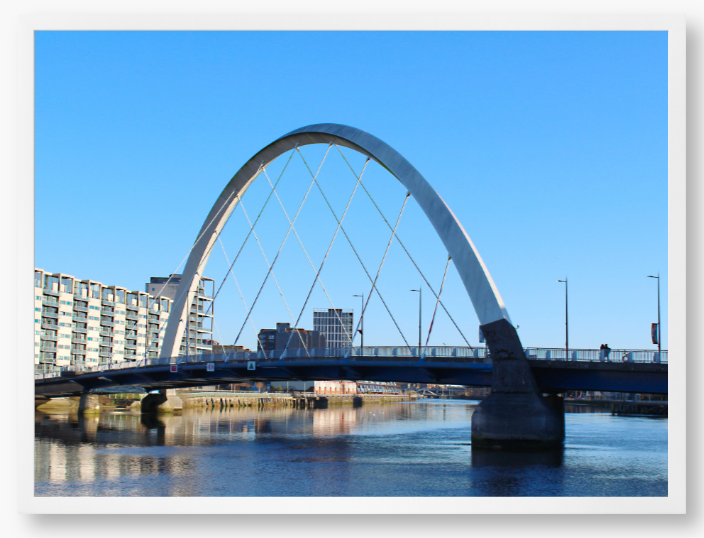 A framed photo of the Glasgow Clyde Arc Bridge over the River Clyde, with a clear blue sky in the background.