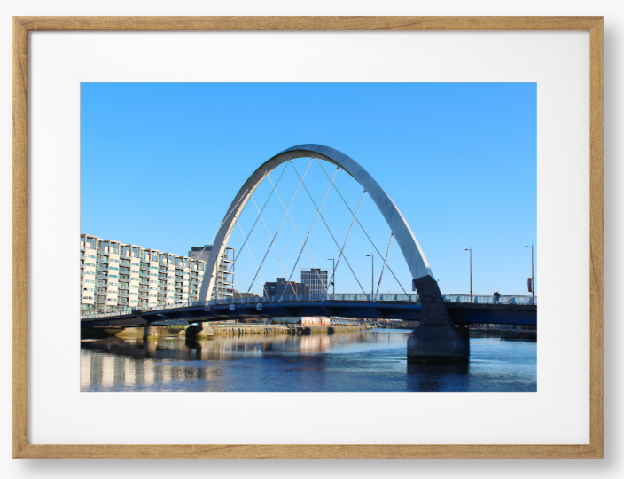 A framed photo of the Glasgow Clyde Arc Bridge over the River Clyde, with a clear blue sky in the background.
