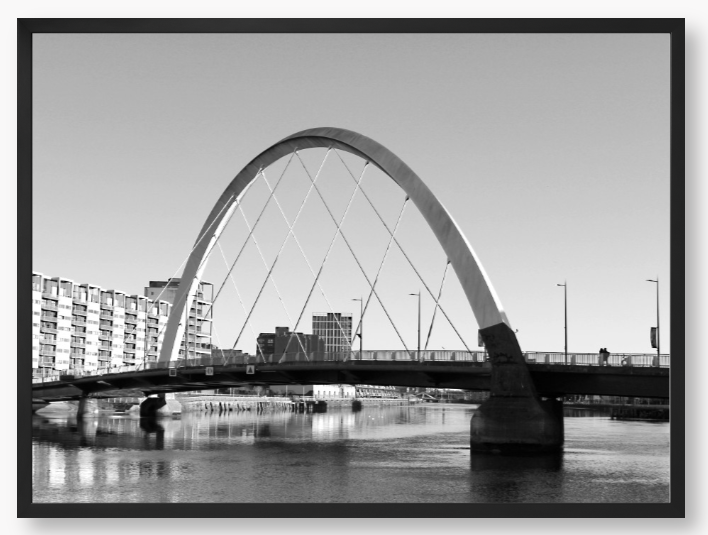 Black and White framed photo of the Glasgow Clyde Arc Bridge over the River Clyde, with a clear sky in the background.