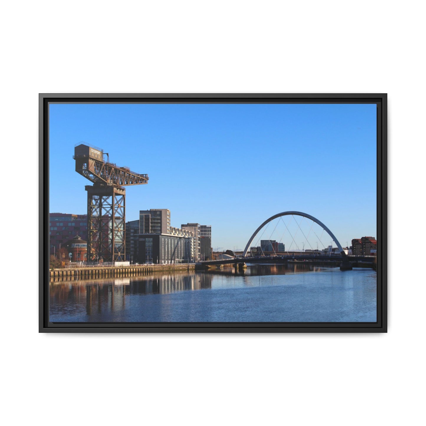 Framed photograph of a cityscape with a crane and a bridge over water.