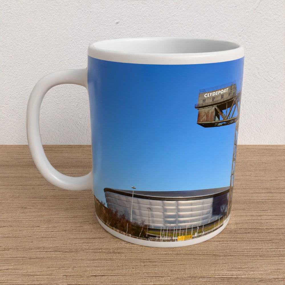 Mug with a printed design of a stadium and blue sky on a wooden surface.