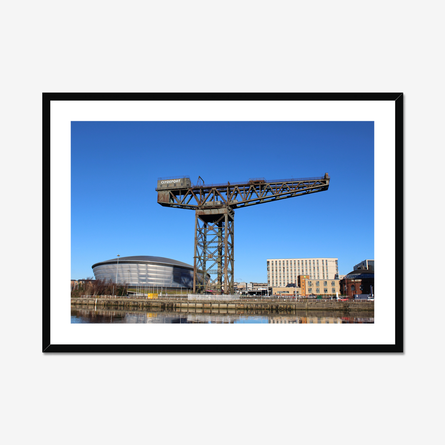 Framed photograph of a large crane with a modern building in the background