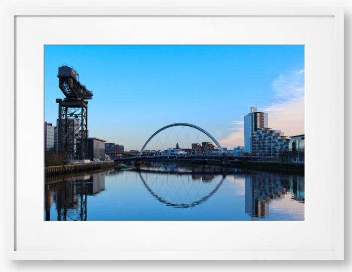 A framed print featuring a photograph of Glasgow's River Clyde with reflections, including a prominent crane and modern cityscape in the background.