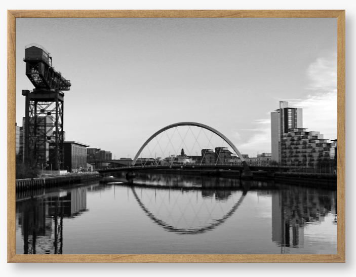 Black and White framed photograph of Glasgow's River Clyde with reflections, including a prominent crane and modern cityscape in the background.