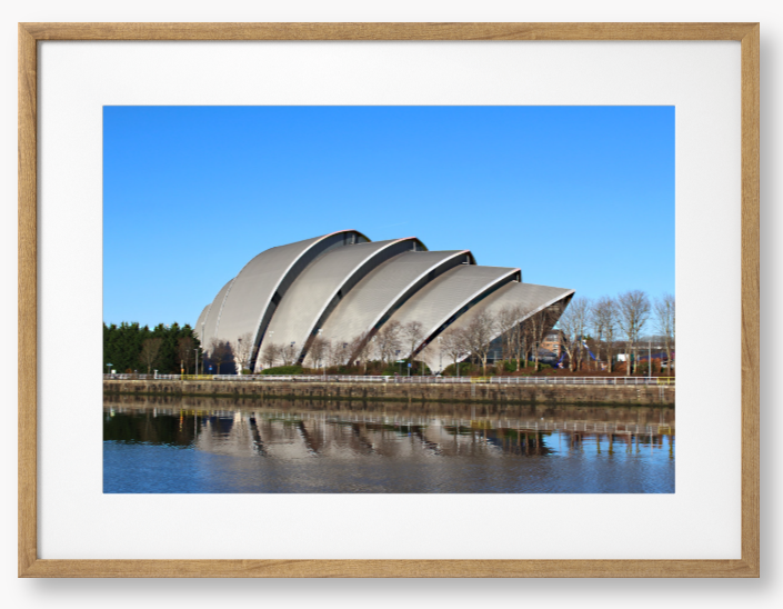 Framed Photo of a Modern architectural building reflected in water with a clear blue sky