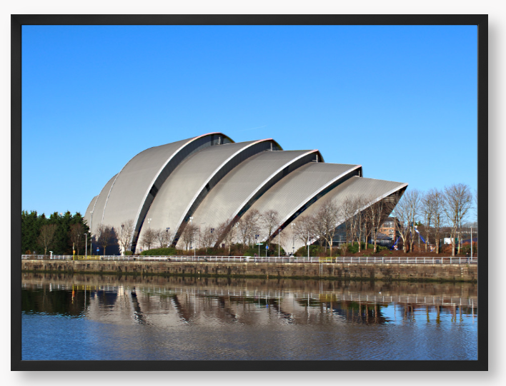 Framed Photo of a Modern architectural building reflected in water with a clear blue sky