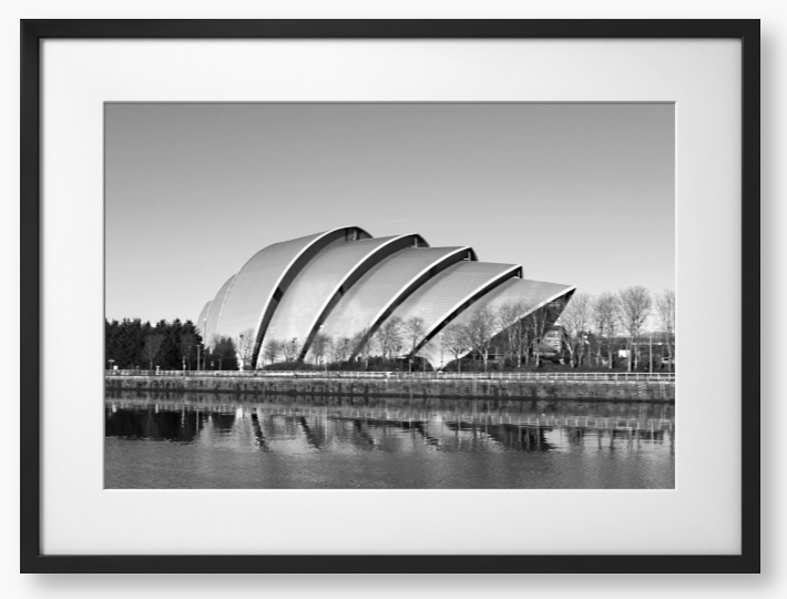 Black and white framed photo of a modern architectural structure reflected in water