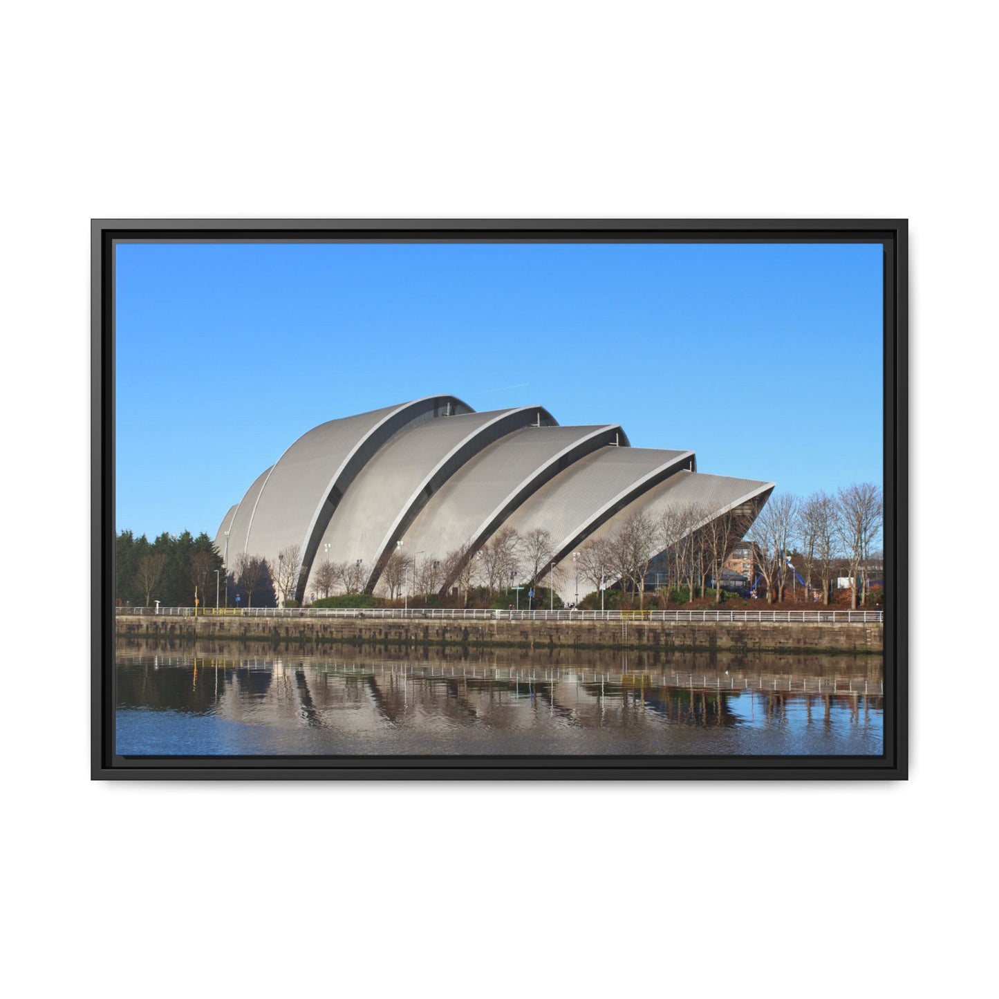 Framed photograph of a modern architectural structure with a blue sky and water reflection.