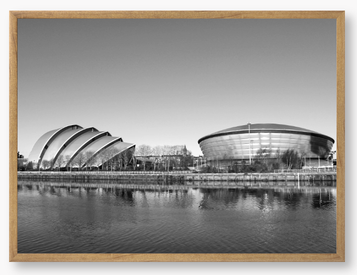 Black and white framed photograph of modern architectural buildings by a body of water.