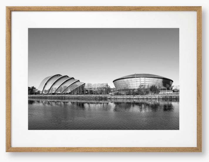 Black and white framed photograph of modern architectural buildings by a body of water.
