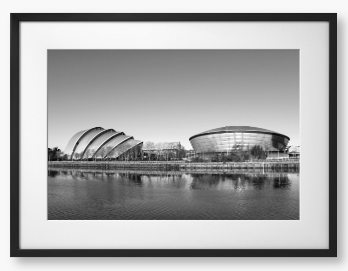 Black and white framed photograph of modern architectural buildings by a body of water.