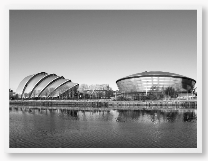 Black and white framed photograph of modern architectural buildings by a body of water.
