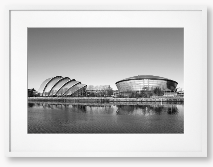 Black and white framed photograph of modern architectural buildings by a body of water.