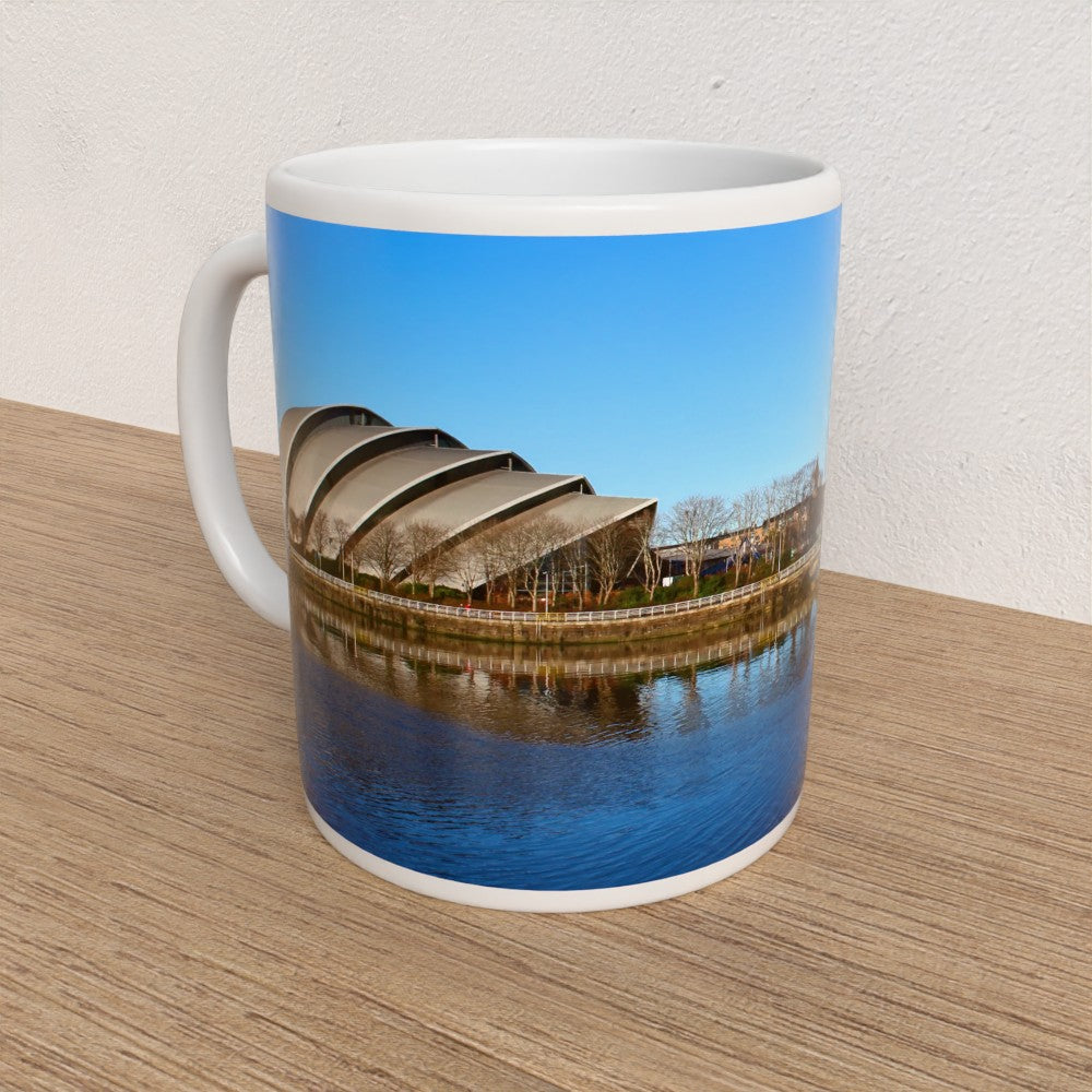 Mug with a scenic design of a building and water on a wooden surface
